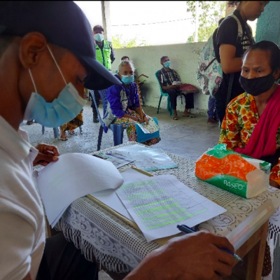 A Government official is putting the paperwork in order before a beneficiary at Suco Dato in Liquica Municipality is referred to the payment desk. 